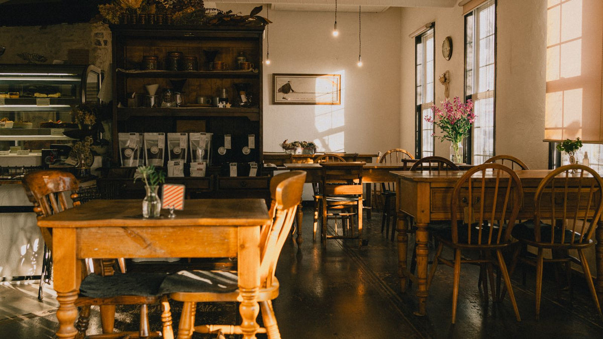 Salle de café chaleureuse avec tables en bois et suspensions