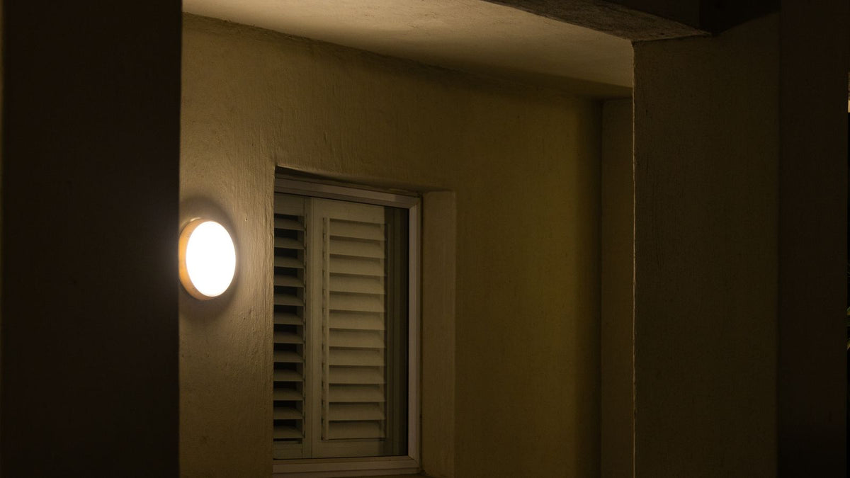 Applique murale douce éclairant une fenêtre à volets le soir