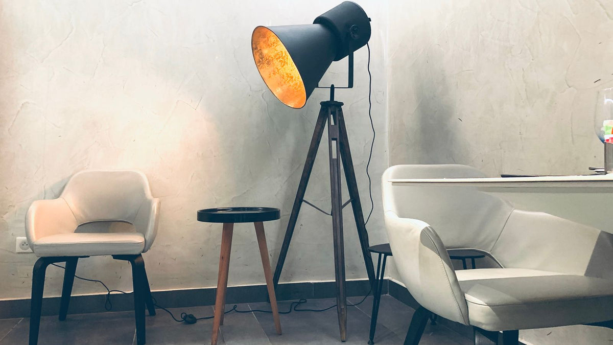 Lampadaire trépied noir dans un salon clair aux matières douces