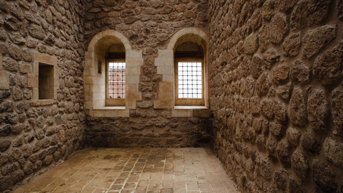 Pièce aux murs en pierre ancienne percés de petites fenêtres