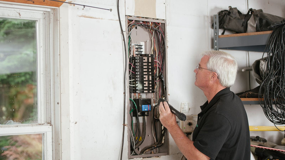 Électricien contrôlant un tableau électrique selon la norme NF C 15-100