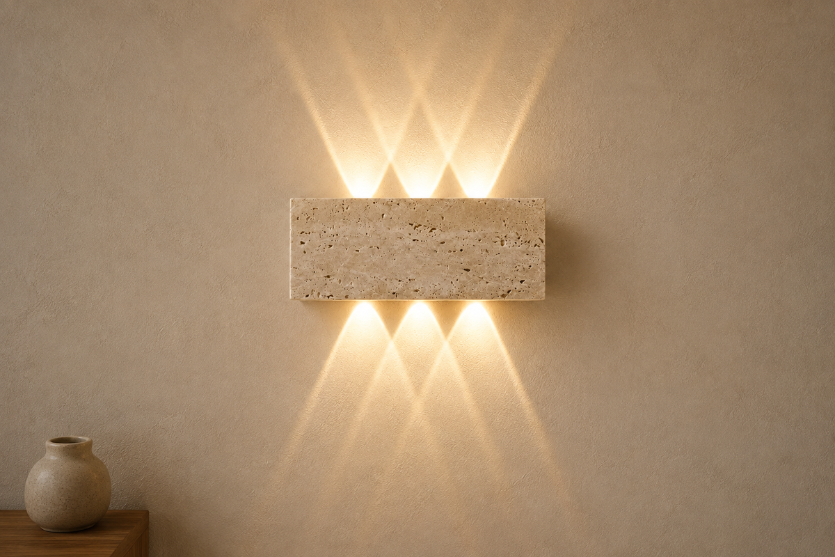 Applique Wabi-Sabi en pierre naturelle allumée sur un mur taupe clair, deux éventails de lumière