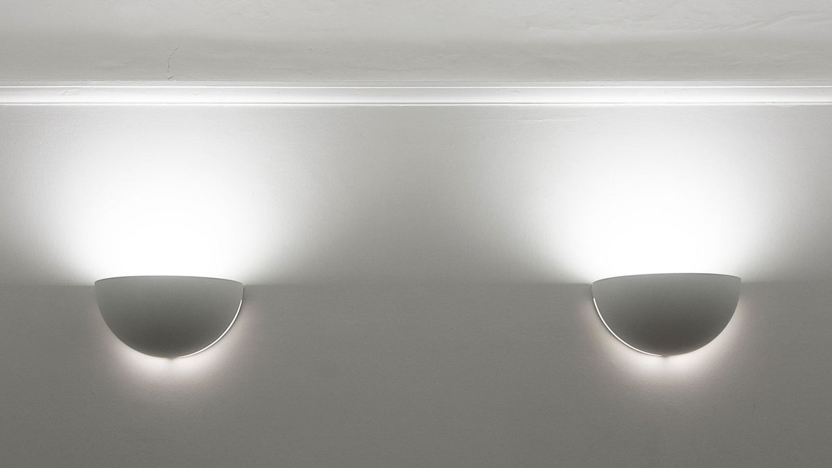 Deux appliques en plâtre blanc diffusant une lumière vers le haut