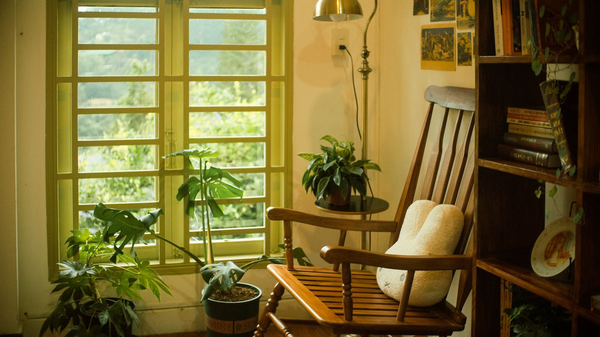 Coin lecture avec fauteuil, plantes et lumière chaude près de la fenêtre