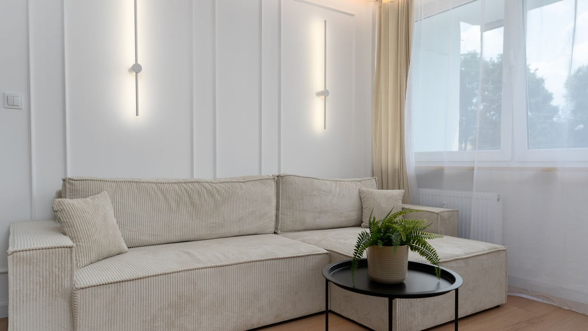 Salon minimaliste au canapé beige éclairé par des appliques modernes