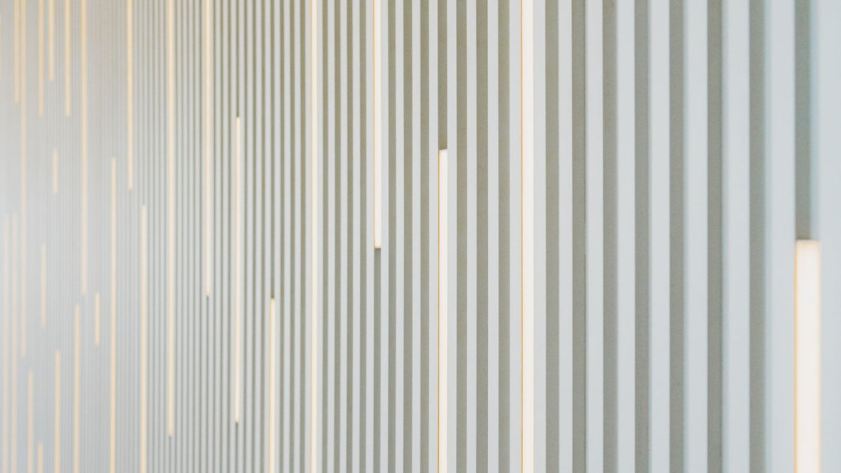 Mur blanc strié de faisceaux lumineux verticaux et réguliers