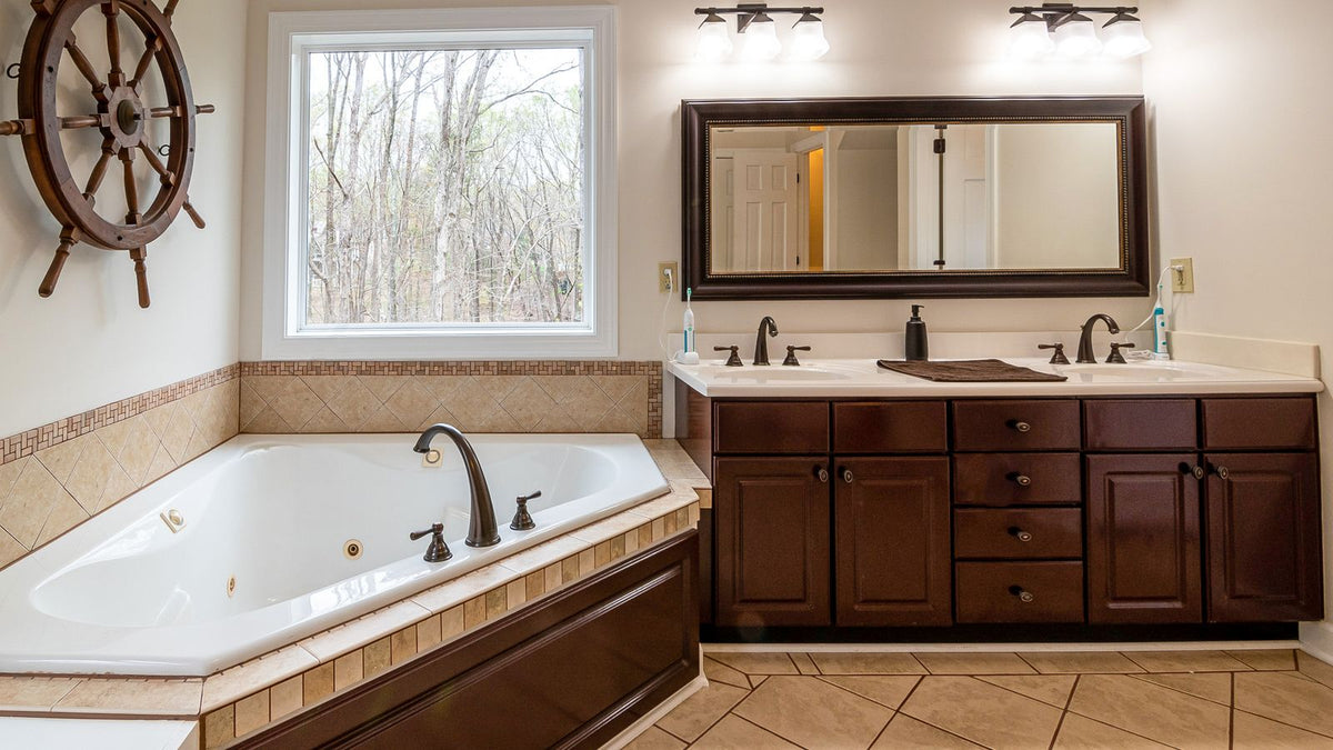 Salle de bain avec baignoire et miroir éclairé au-dessus du double vasque