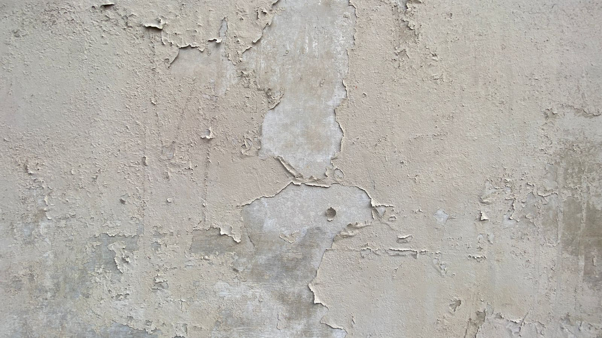 Mur en plâtre texturé aux traces de peinture, avant rebouchage