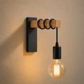Applique retro en bois et metal noir, ampoule a filament, allumee sur un mur en enduit