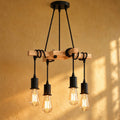 Lustre salon vintage bois et métal noir, 4 ampoules E27 allumées devant un mur jaune