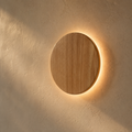 Applique circulaire en bois nordique allumée, anneau de lumière sur un mur en enduit crème #rond