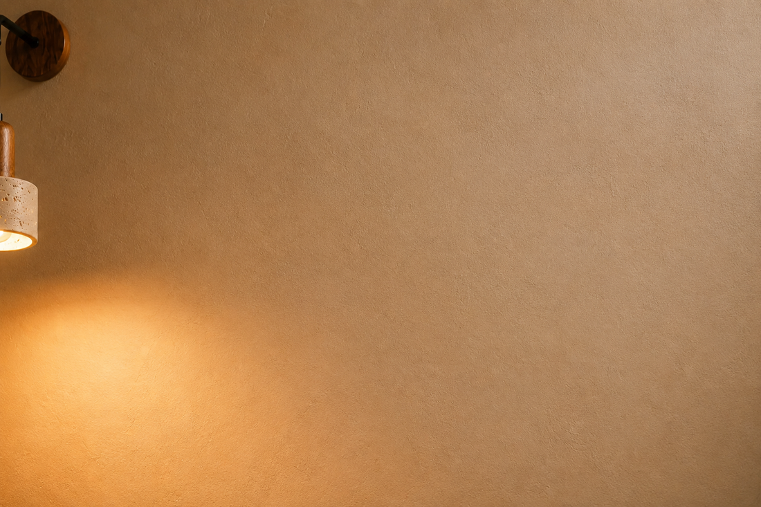 Mur à la chaux crème révélé par la lumière rasante de l'applique rétro en pierre