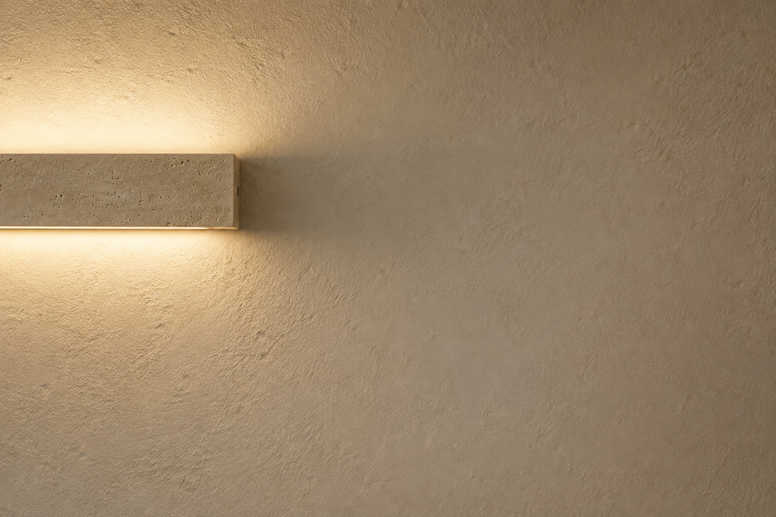 Mur à la chaux crème révélé par la lumière rasante de l'applique en pierre naturelle