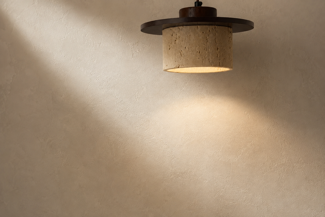 Mur à la chaux crème révélé par la lumière chaude et rasante de la suspension